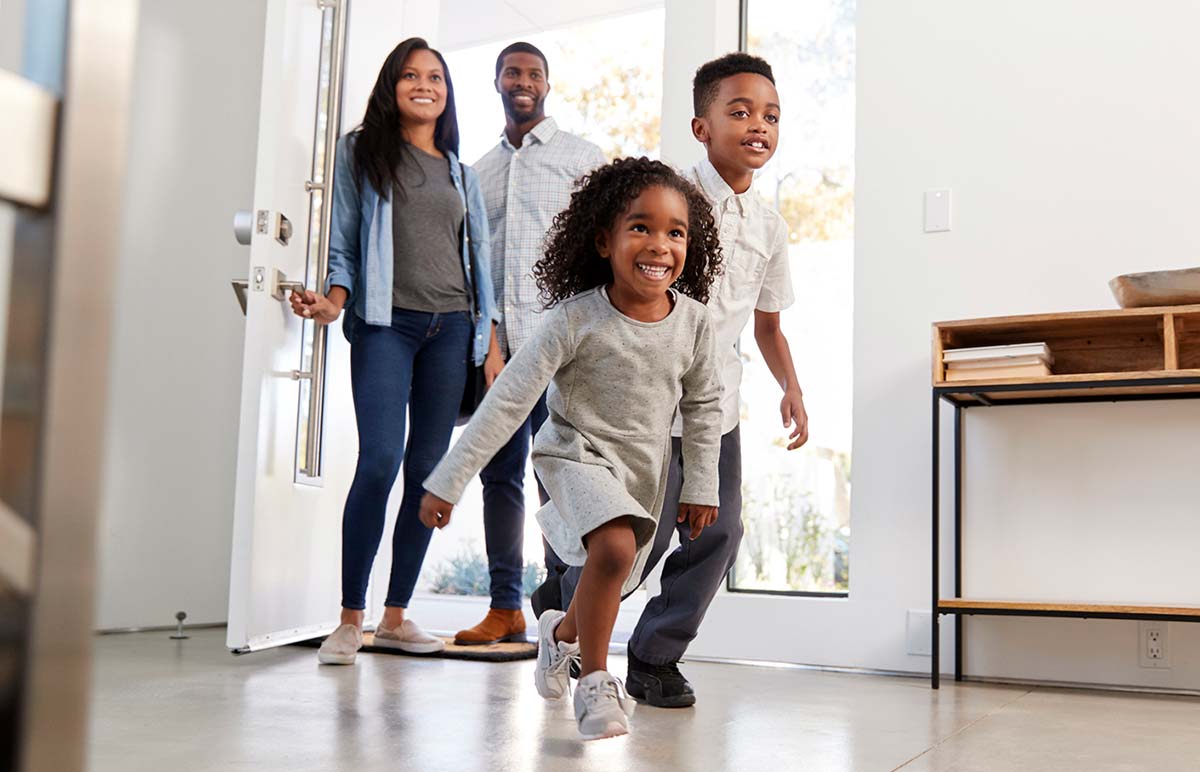 Family of four opening there door to their new house and running inside after a thorough inspection by our home inspectors